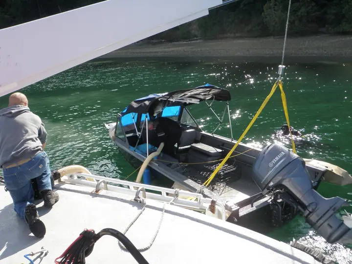 Small aluminum boat alongside CASCADE during a lift operation